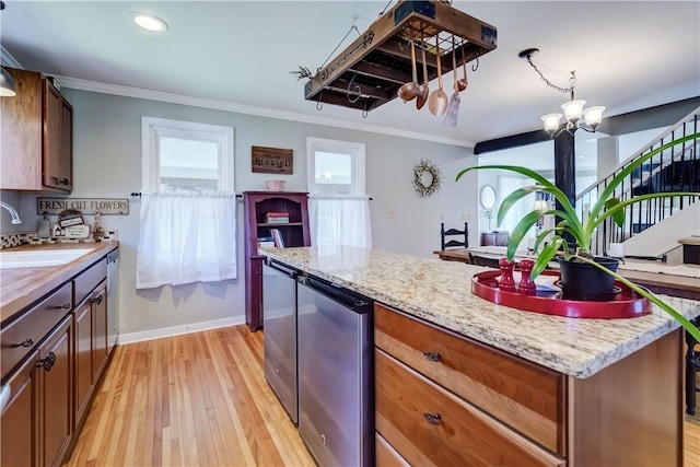 kitchen featuring crown molding, refrigerator, a center island, a sink, and light wood finished floors