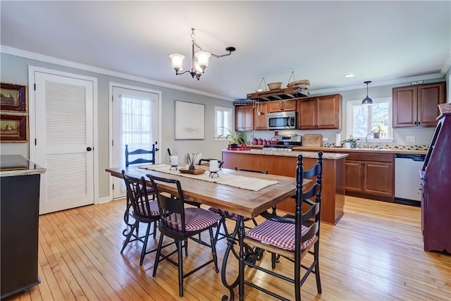 dining space with light wood-style floors, ornamental molding, and a notable chandelier