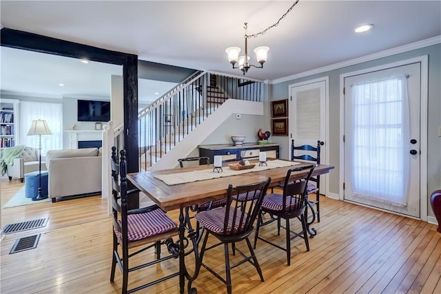 dining area featuring an inviting chandelier, ornamental molding, stairs, and visible vents