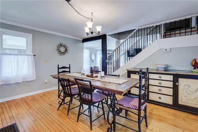 dining area with a chandelier, baseboards, light wood-type flooring, ornamental molding, and stairway