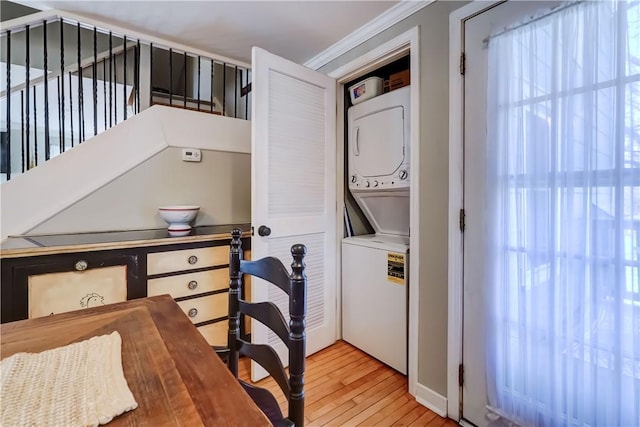 interior space featuring crown molding, laundry area, stacked washing maching and dryer, and light wood finished floors