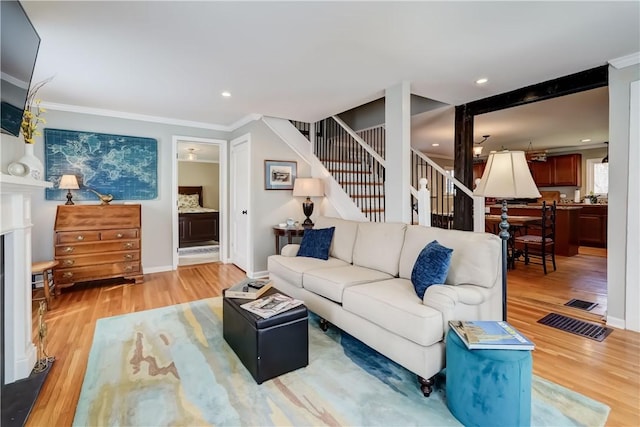 living room featuring crown molding, a fireplace, wood finished floors, stairway, and baseboards