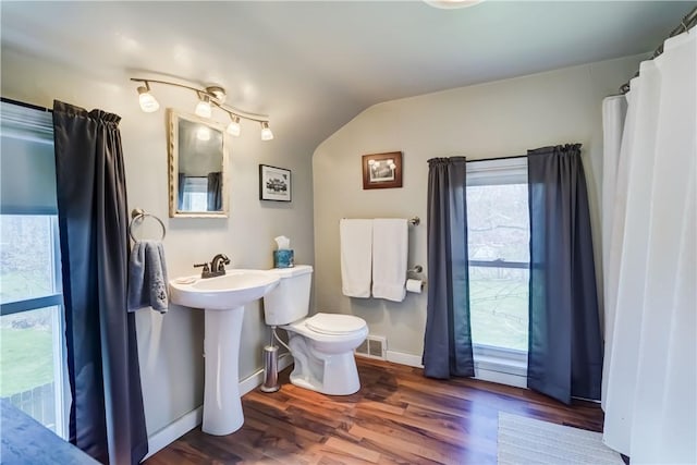 bathroom featuring visible vents, wood finished floors, toilet, baseboards, and vaulted ceiling