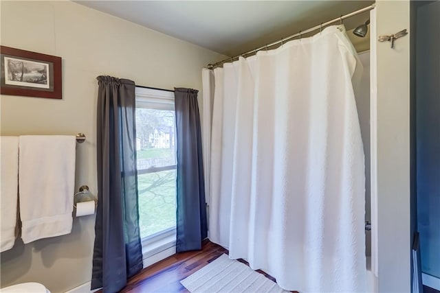 full bath featuring a shower with shower curtain, a wealth of natural light, and wood finished floors