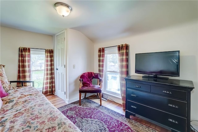 bedroom featuring light wood-type flooring, baseboards, lofted ceiling, and multiple windows