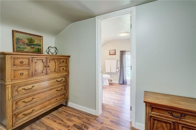 interior space featuring baseboards, light wood-style flooring, and vaulted ceiling