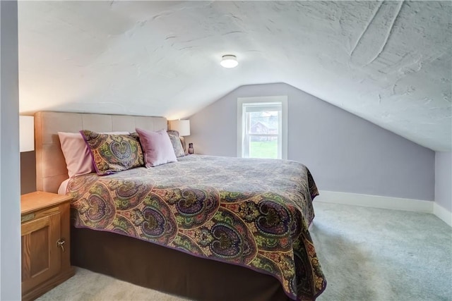 bedroom with baseboards, light colored carpet, and vaulted ceiling