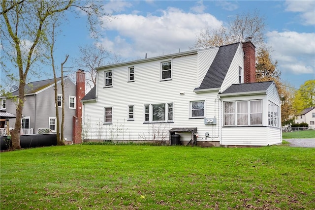 back of house with a shingled roof, a yard, and a chimney