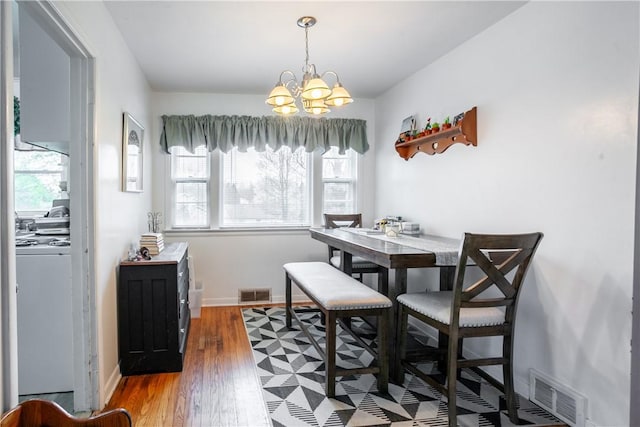 dining area featuring wood finished floors, a notable chandelier, washer / clothes dryer, and visible vents