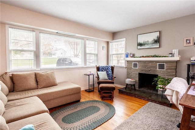 living area featuring baseboards, wood finished floors, and a fireplace