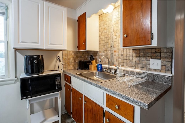kitchen featuring a sink, white cabinets, black microwave, and tasteful backsplash