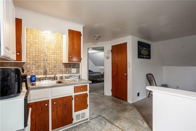 kitchen featuring backsplash, baseboards, a sink, and light countertops