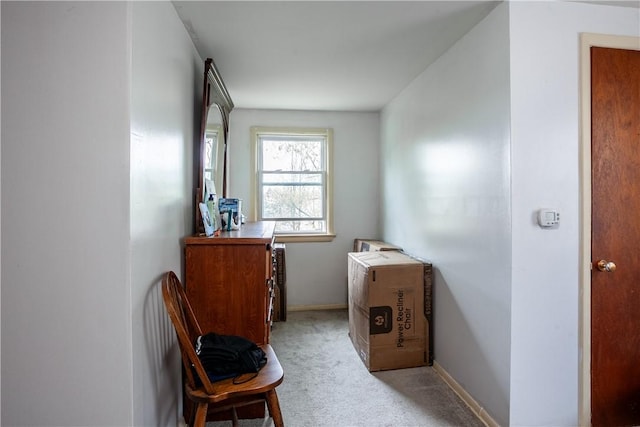 hall with baseboards and light carpet