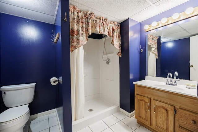bathroom featuring vanity, toilet, tile patterned floors, a drop ceiling, and a shower stall