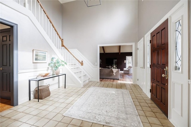 entryway with tile patterned flooring, stairs, and a high ceiling