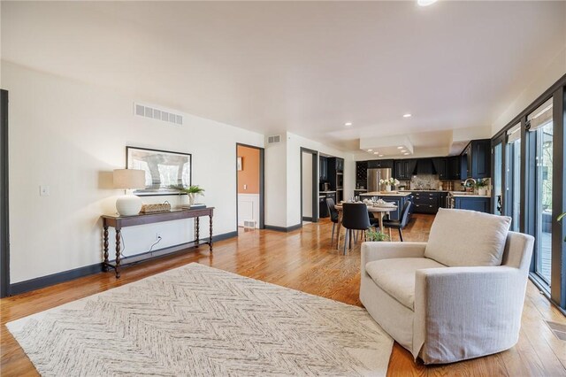 living area featuring recessed lighting, baseboards, light wood finished floors, and visible vents