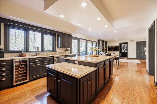 kitchen with a sink, dishwasher, beverage cooler, recessed lighting, and a kitchen island