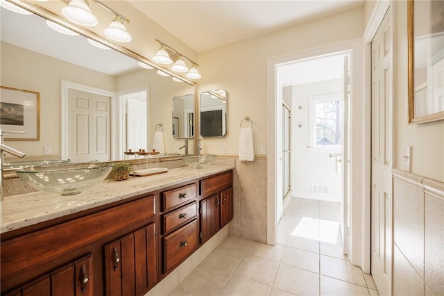 full bath featuring a sink, double vanity, tile patterned floors, a shower stall, and visible vents