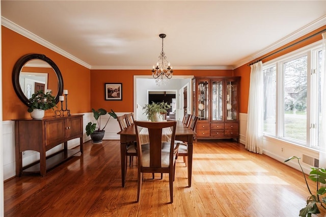 dining area featuring crown molding, light wood-style flooring, and a chandelier