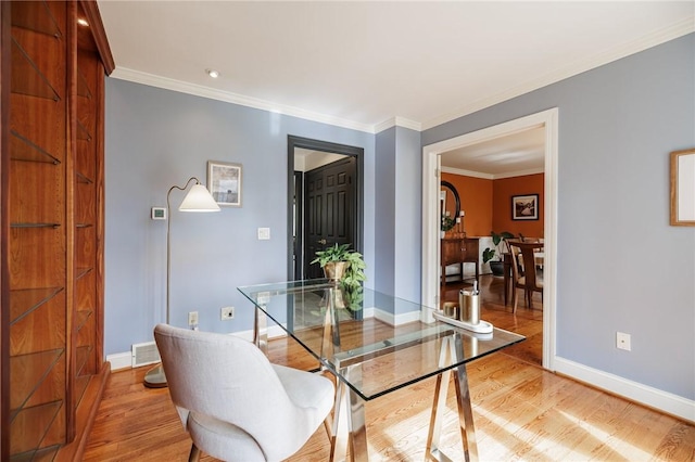 dining room featuring crown molding, baseboards, and light wood-style floors