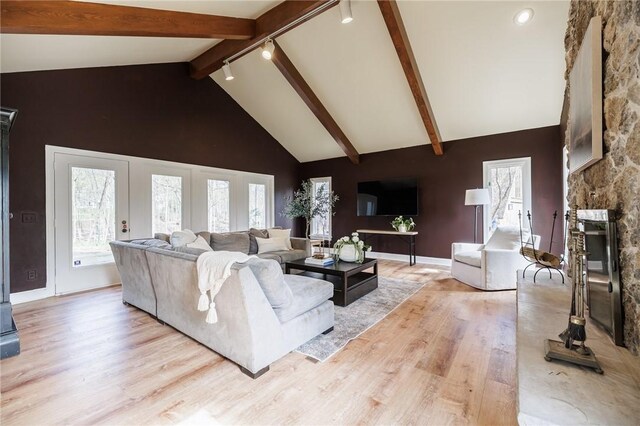 living area featuring high vaulted ceiling, plenty of natural light, beamed ceiling, and wood finished floors