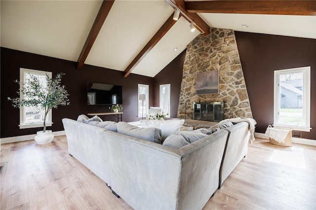 living room featuring light wood-style flooring, beam ceiling, and a wealth of natural light