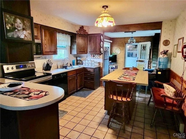 kitchen featuring light countertops, stainless steel appliances, wallpapered walls, and a sink