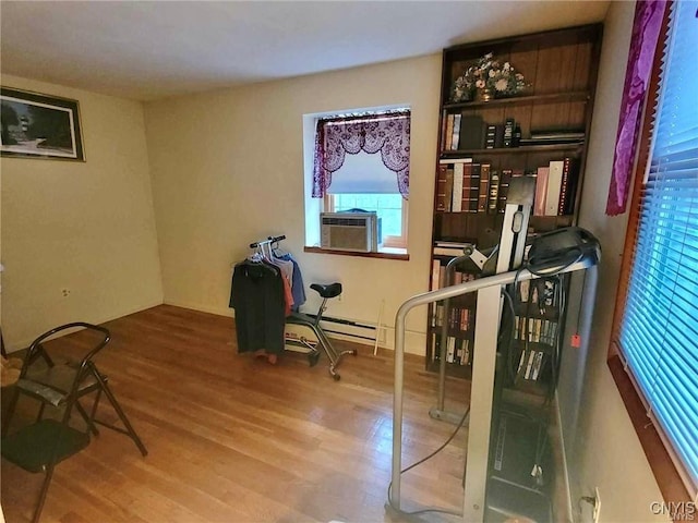 interior space featuring wood finished floors, baseboard heating, and cooling unit