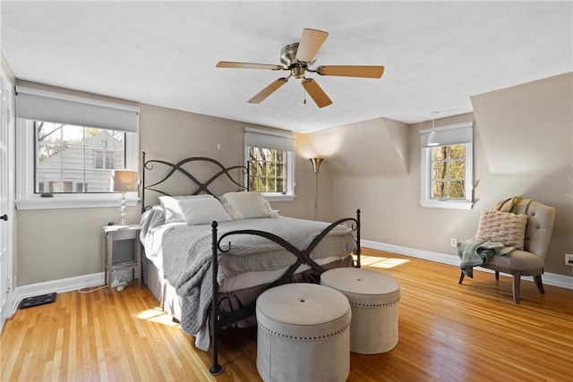 bedroom with baseboards, a ceiling fan, wood finished floors, and multiple windows