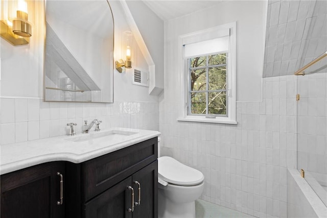 bathroom featuring visible vents, tile walls, a wainscoted wall, vanity, and toilet