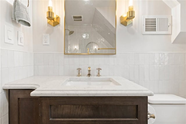bathroom featuring vanity, toilet, tile walls, and visible vents