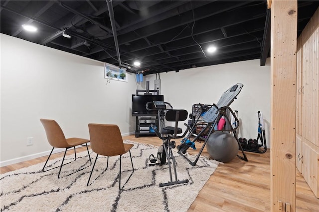 exercise room with baseboards and wood finished floors