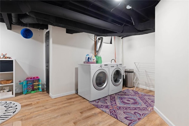 laundry area featuring washer and dryer, laundry area, baseboards, and wood finished floors