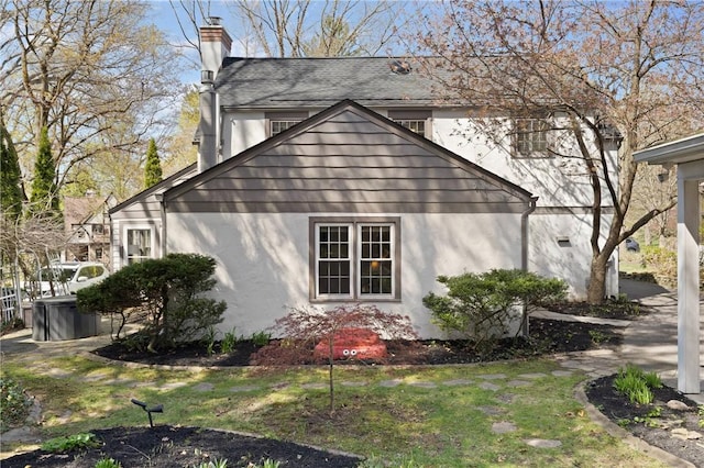 view of property exterior with a chimney and stucco siding