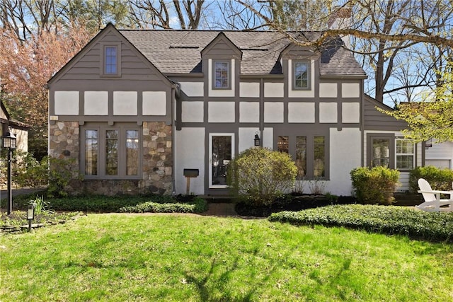 back of house featuring a shingled roof, stucco siding, and a yard
