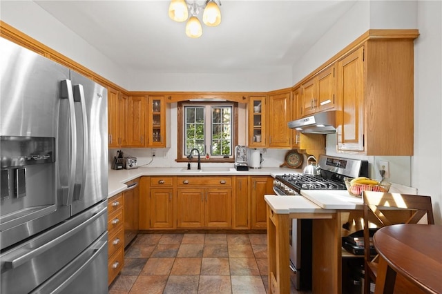 kitchen featuring a sink, light countertops, brown cabinetry, stainless steel appliances, and under cabinet range hood