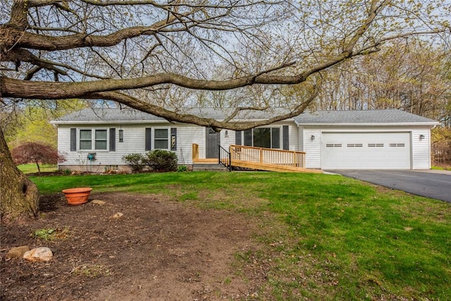 ranch-style home featuring an attached garage, a front lawn, and aphalt driveway