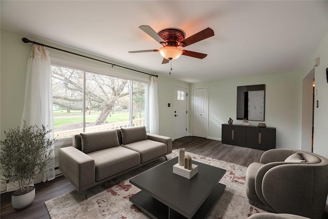 living area with baseboards, ceiling fan, and wood finished floors