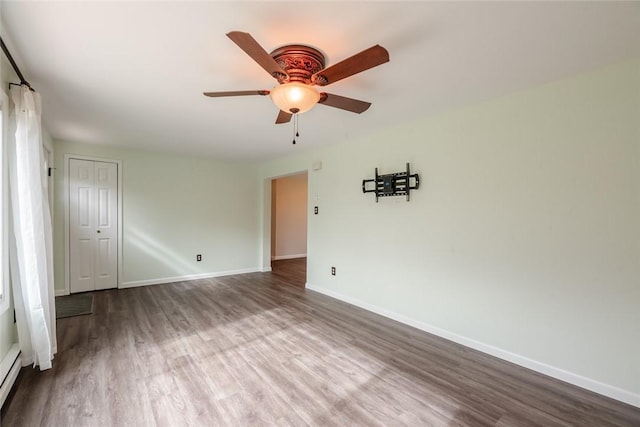 spare room featuring a ceiling fan, baseboards, and wood finished floors