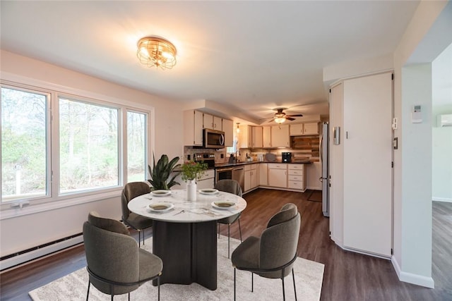 dining room with baseboards, dark wood-style flooring, ceiling fan, and baseboard heating