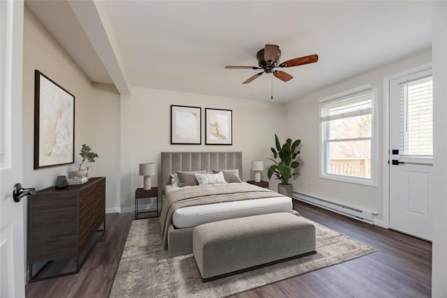 bedroom featuring a baseboard heating unit, multiple windows, and dark wood finished floors