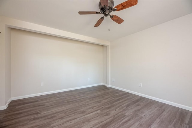 empty room with a ceiling fan, baseboards, and dark wood-type flooring