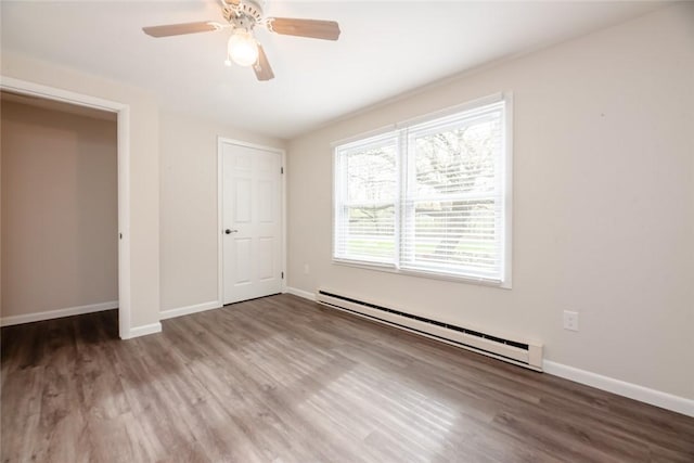 unfurnished bedroom featuring a ceiling fan, baseboards, baseboard heating, and wood finished floors