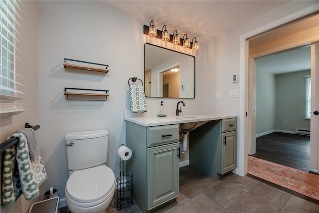 half bathroom featuring toilet, baseboard heating, tile patterned flooring, and vanity