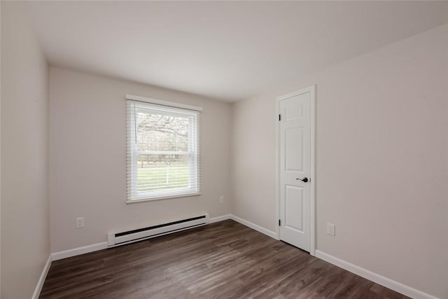 spare room with baseboards, a baseboard heating unit, and dark wood-style floors