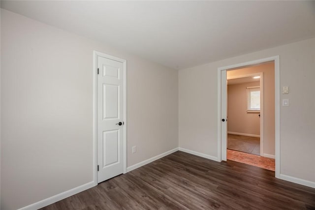 spare room featuring baseboards and dark wood-style floors