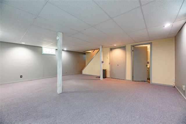 basement featuring baseboards, carpet, stairs, and a paneled ceiling