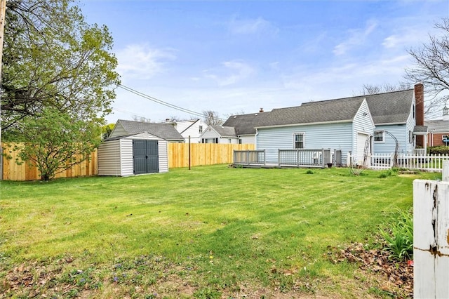 view of yard with an outdoor structure, a fenced backyard, a shed, and a wooden deck