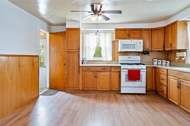 kitchen with a wealth of natural light, a ceiling fan, brown cabinets, and white appliances
