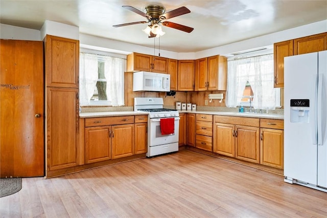 kitchen with white appliances, brown cabinets, plenty of natural light, and light countertops